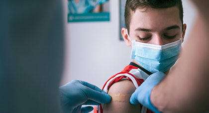 band-aid being placed on boy's arm after vaccine shot