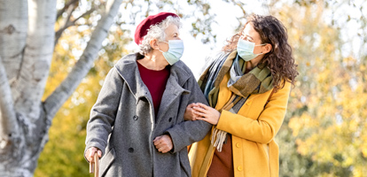 two women wearing masks walking in the park