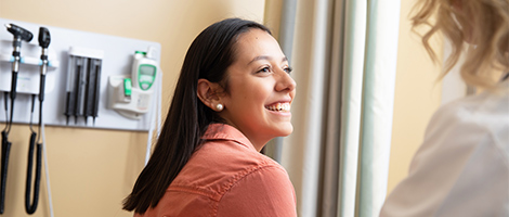 A woman smiling as she speaks with her doctor.