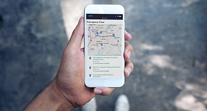 A person holding a phone showing the locations of AHN Facilities near him.