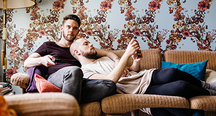 young man laying on couch using his smartphone to message his doctor on MyChart
