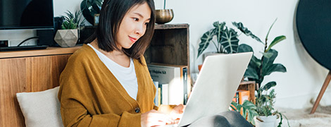 woman smiling as she uses her laptop to sign up for MyChart