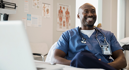 image of a nurse sitting in front of a computer smiling