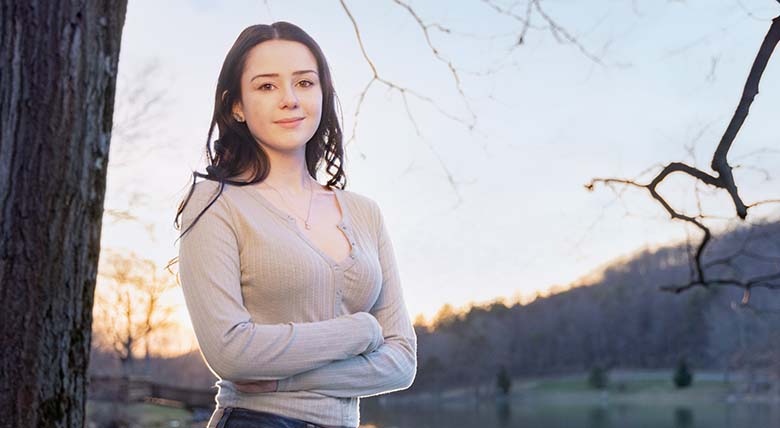  AHN patient Rachel Wilson having her photo taken standing at the side of a body of water next to a tree