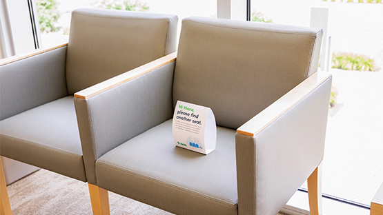 social distancing sign on chair in waiting room
