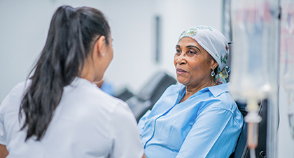 nurse talking to an older cancer patient during treatment