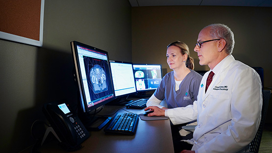 two physicians reviewing a patient’s scans on a computer