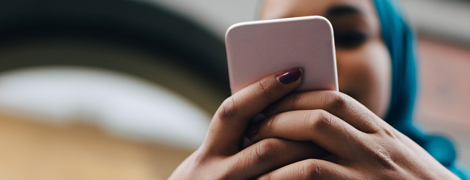 woman typing phone number into her cell phone to call