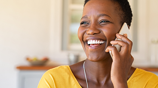 black woman smiling while she places a call on her cell phone