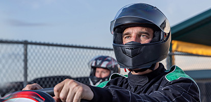 man wearing a helmet behind the wheel of a go-kart