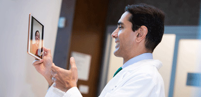 Cardiologist holding tablet while video chatting with a patient 