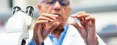 image of a doctor looking at a specimen under a microscope