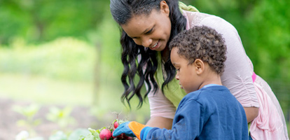 woman holding radishes as she gardens with her son