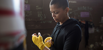 woman wrapping her hands in front of punching bag