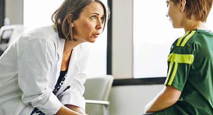 physician talking to a young student athlete in an exam room