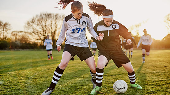 two female student athletes playing soccer