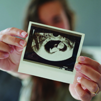 woman holding up a sonogram image of her baby