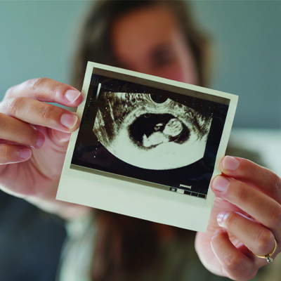 woman holding up a sonogram image of her baby