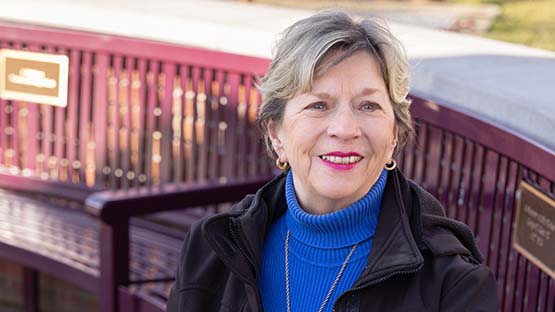 Woman smiling at the camera as her photo is taken on a bench outside