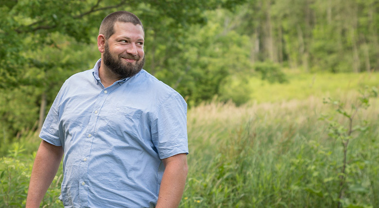 man smiling at the camera as his photo is taken outdoors