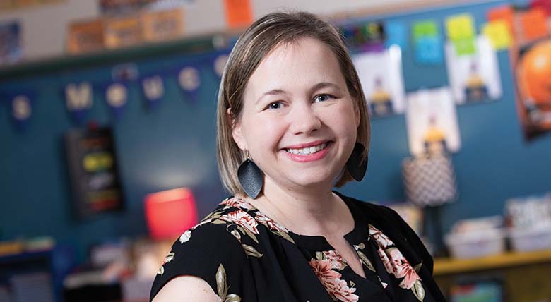 Cancer survivor, AHN patient, and teacher KD Meucci smiling at the camera as her photo is taken in her classroom